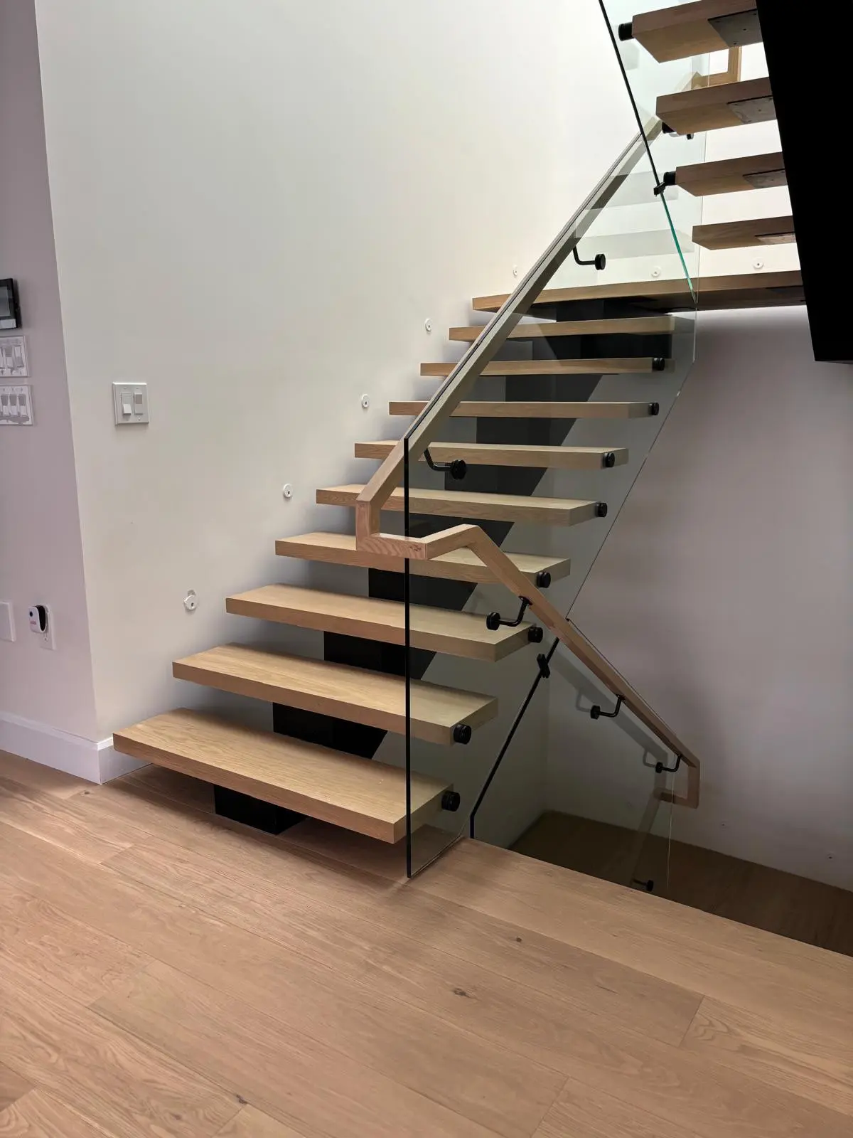 Floating staircase with thick custom wood treads and glass railing
